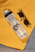 Translucent drinking bottle mockup resting on a beach towel. Features a customizable lapel pin for presenting beverage brands, packaging concepts, and outdoor lifestyle identities.