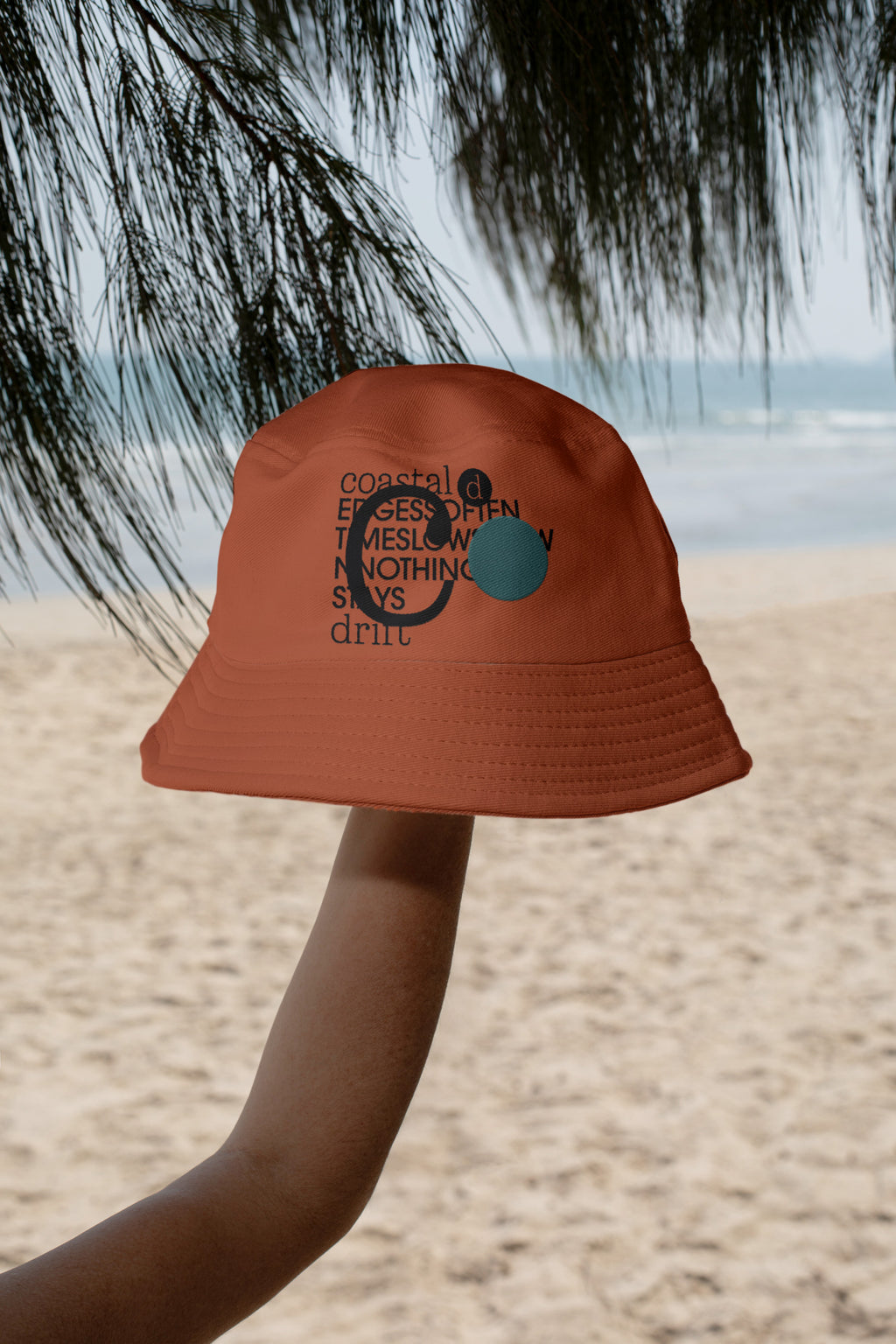 Bucket hat mockup held by hand against the coastline of Hua Hin, Thailand. Includes a realistic embroidery effect for presenting logos, apparel branding, and merchandise designs.