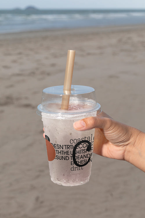 Plastic cup mockup held by hand at the beach. Built for showcasing beverage branding, logos, packaging, and summer lifestyle concepts.