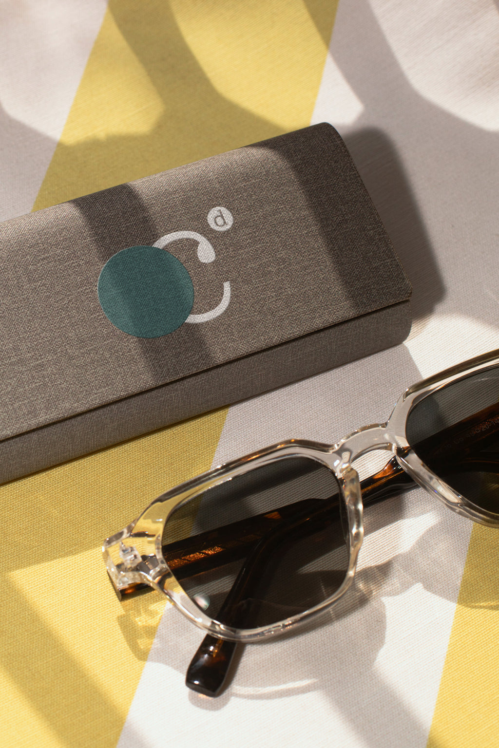 Eyewear case mockup resting on a beach towel beside sunglasses in Hua Hin, Thailand. Built for showcasing eyewear brands, fashion accessories, lifestyle products, and premium branding concepts.