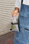 Street-style close-up of a male hand holding Thai coffee in a plastic bag.