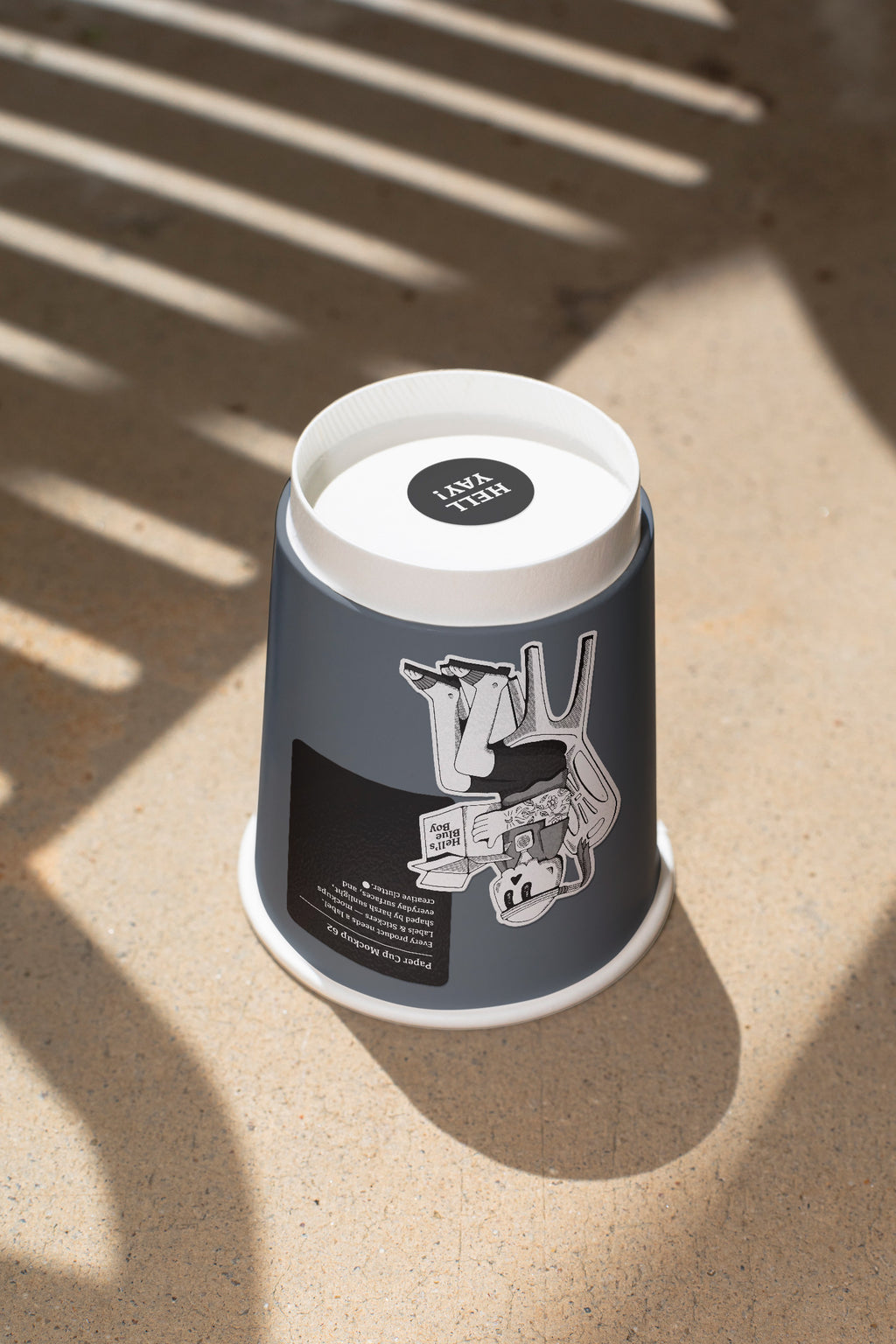 Paper coffee cup mockup featuring stickers placed directly on the cup, photographed under harsh sunlight.
