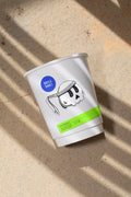 Paper coffee cup mockup featuring stickers placed directly on the cup, photographed under harsh sunlight.