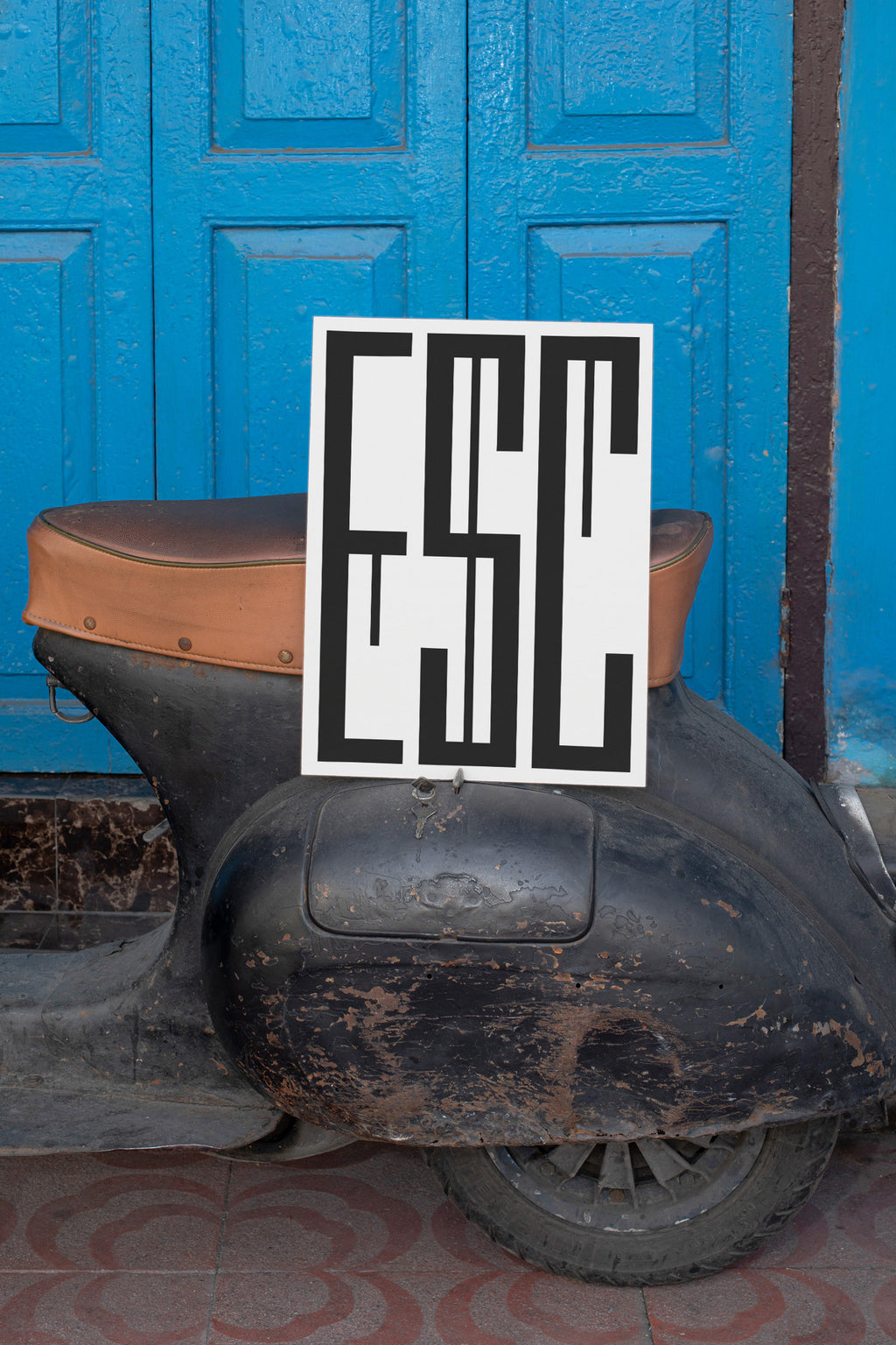 Poster mockup leaning against a vintage black Vespa.