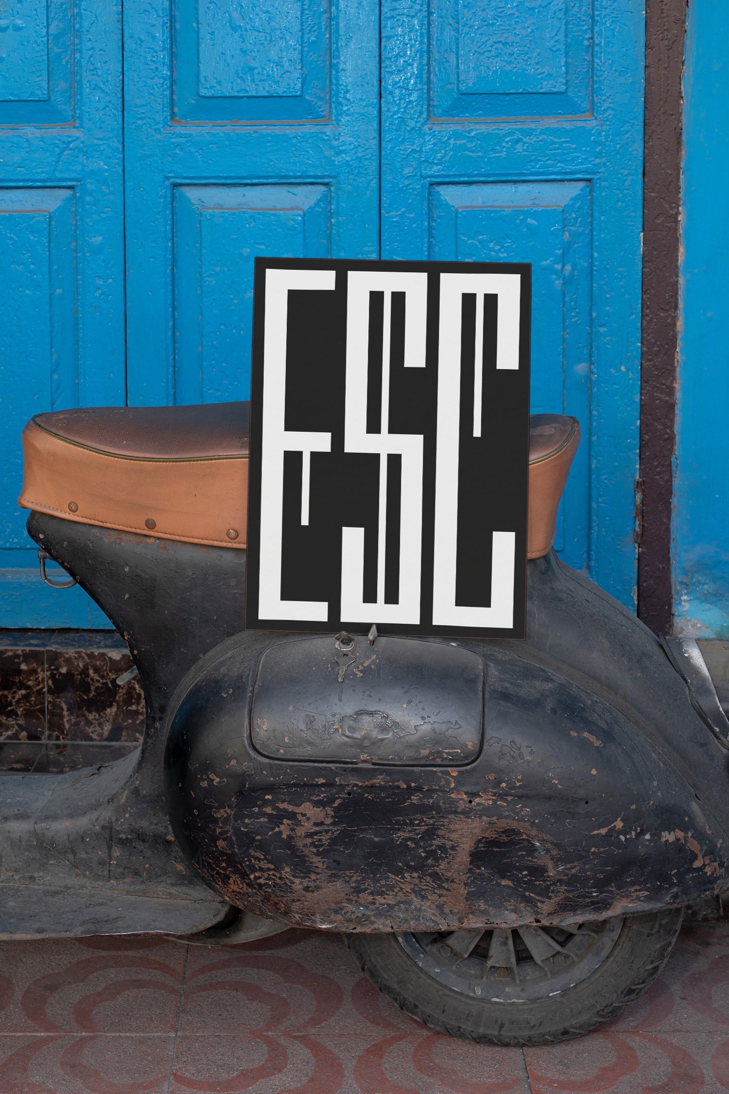 Poster mockup leaning against a vintage black Vespa.