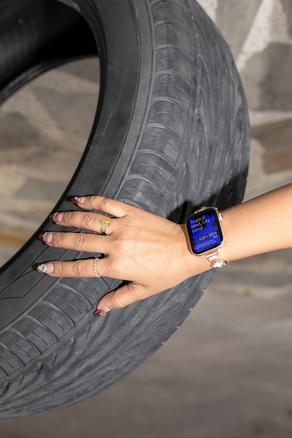 Lifestyle smartwatch mockup featuring a woman’s hand with jewelry wristband holding an SUV tire.