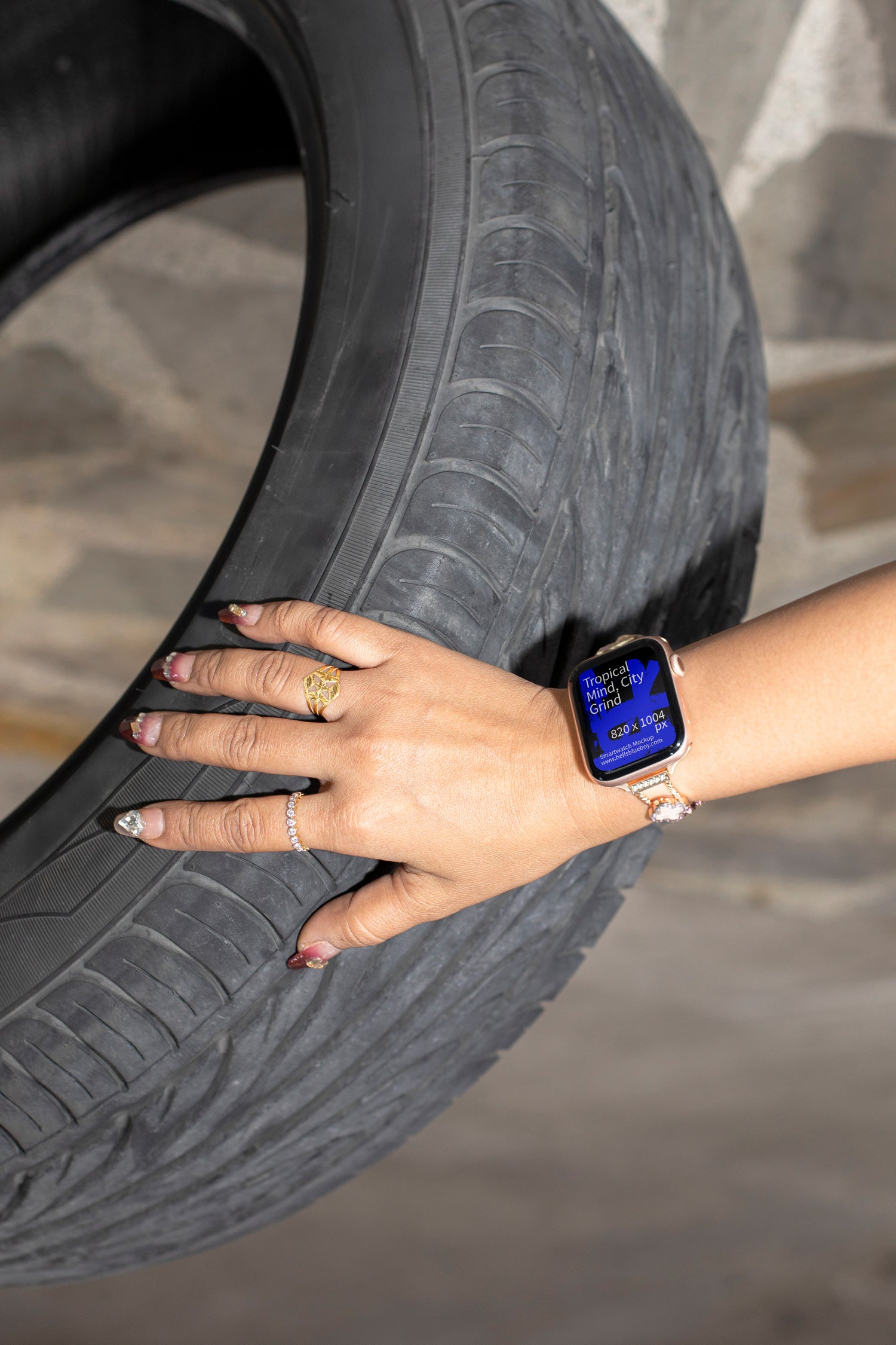 Lifestyle smartwatch mockup featuring a woman’s hand with jewelry wristband holding an SUV tire.