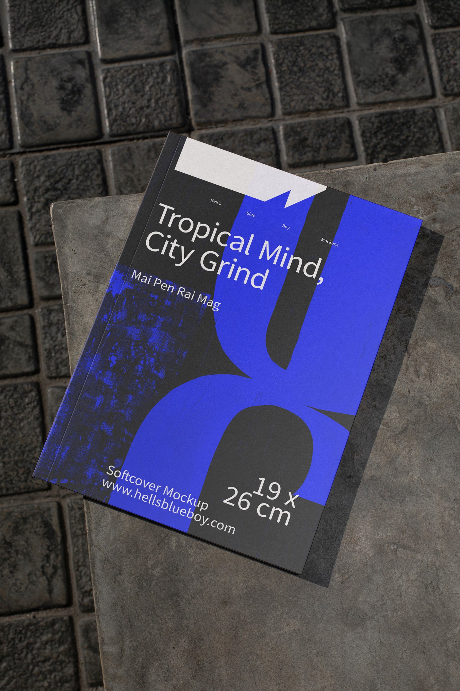 Softcover magazine mockup placed on dark brick tiles.