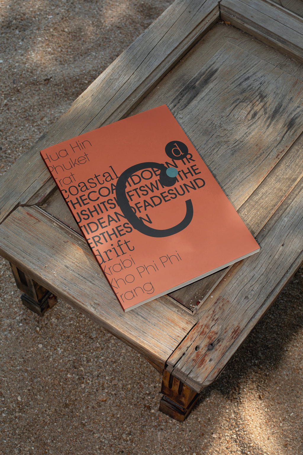 Softcover magazine mockup resting on a wooden table at the beach. Built for showcasing editorial layouts, magazine covers, branding, photography, and print concepts.