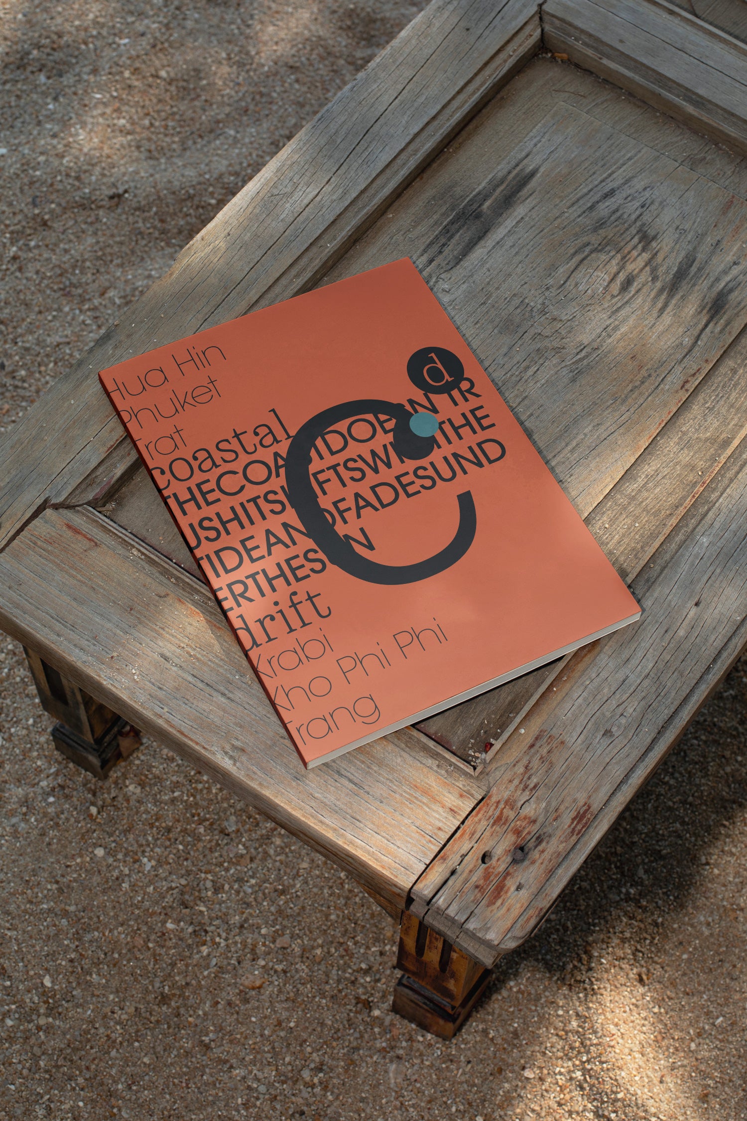 Softcover magazine mockup resting on a wooden table at the beach. Built for showcasing editorial layouts, magazine covers, branding, photography, and print concepts.
