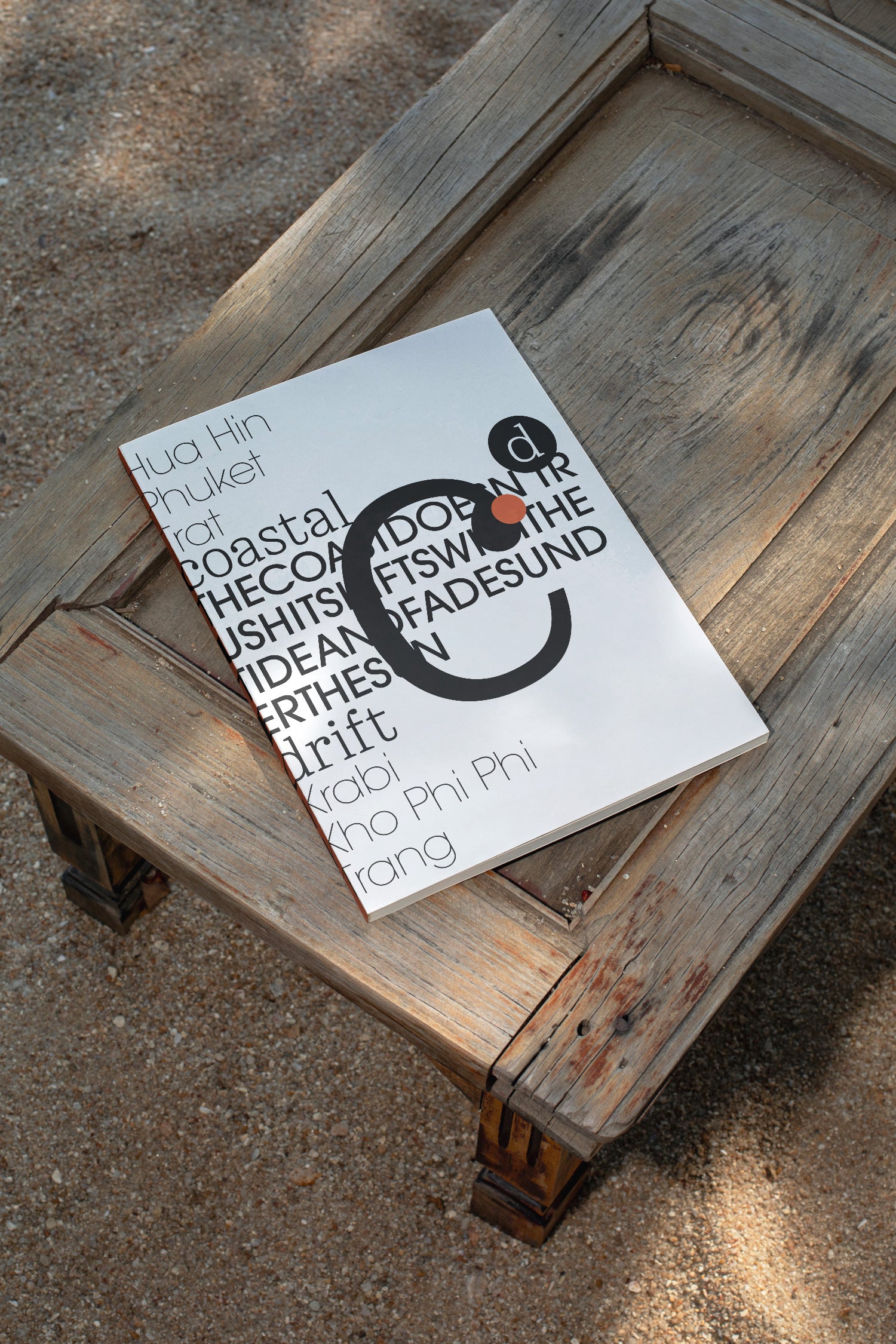 Softcover magazine mockup resting on a wooden table at the beach. Built for showcasing editorial layouts, magazine covers, branding, photography, and print concepts.
