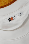 Close-up of a T-shirt label mockup resting on a beach towel. Built for showcasing woven labels, apparel branding, garment details, and fashion identities.