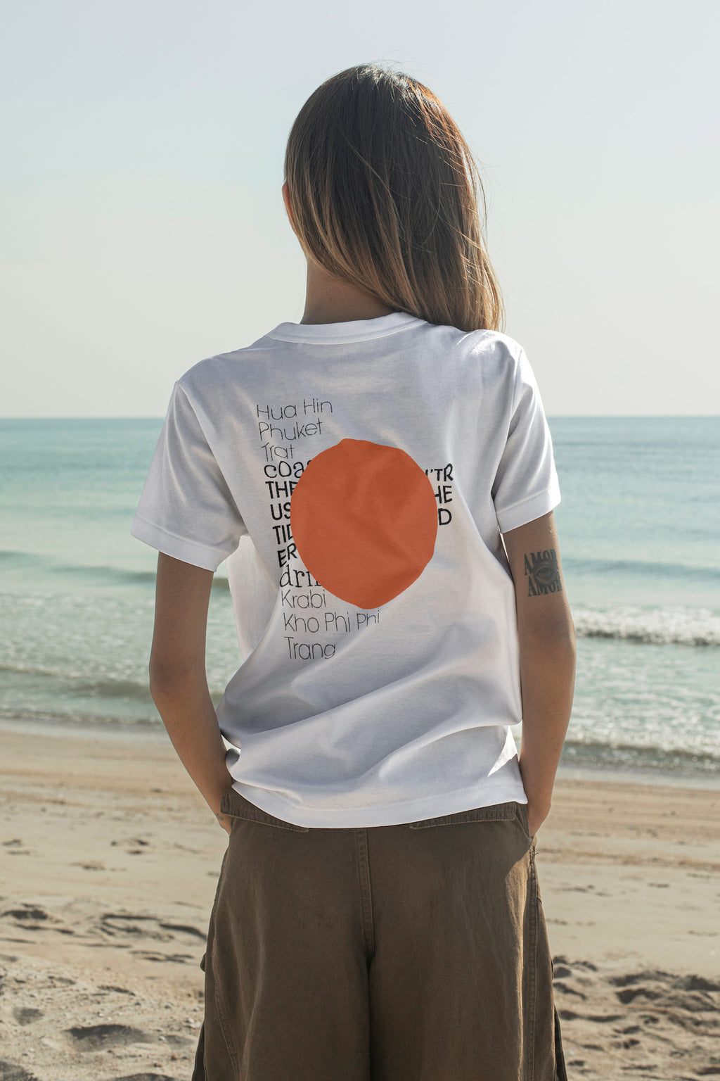 Fashion T-shirt mockup shown from the back while facing the open ocean. Built for showcasing back graphics, apparel branding, fashion collections, merchandise, and lifestyle identities.