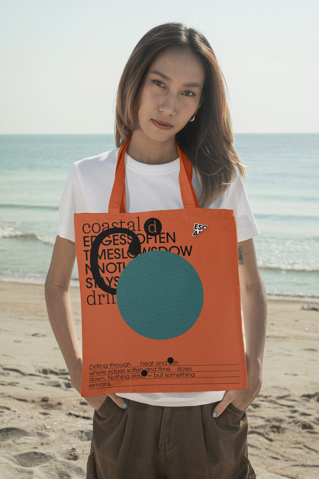 Tote bag mockup styled around the neck at the beach. Designed for presenting fashion brands, merchandise, lifestyle identities, and retail collections.