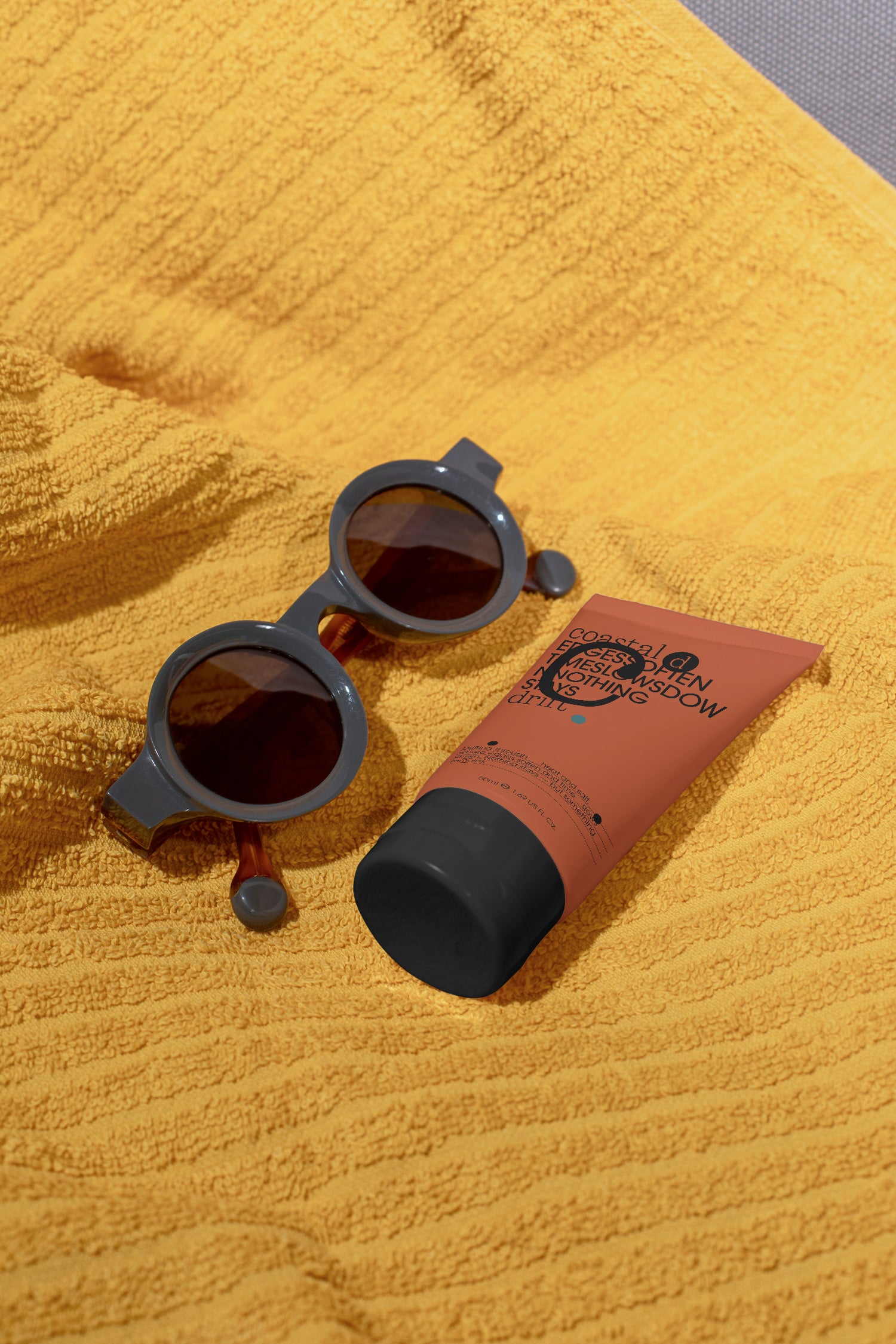 Sunscreen tube mockup resting on a beach towel beside sunglasses. Built for showcasing cosmetic packaging, skincare brands, wellness products, and lifestyle concepts.