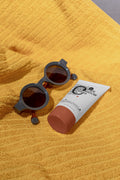 Sunscreen tube mockup resting on a beach towel beside sunglasses. Built for showcasing cosmetic packaging, skincare brands, wellness products, and lifestyle concepts.