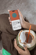 iPhone mockup held by hand while enjoying a fresh coconut. Built for showcasing app interfaces, branding, wallpapers, social media concepts, and digital presentations.